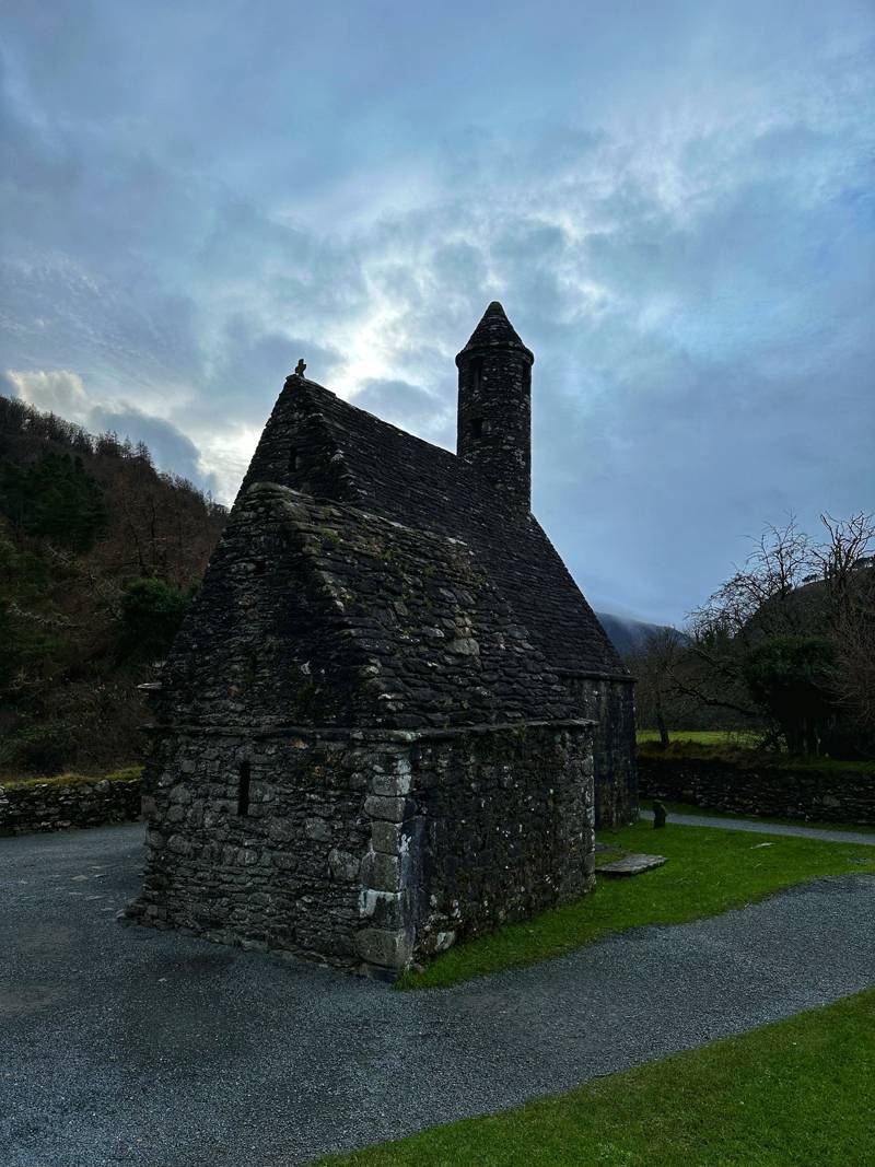 An old stone church with a round tower under a cloudy sky