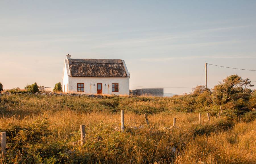 A whitewashed thatched cottage in golden evening light